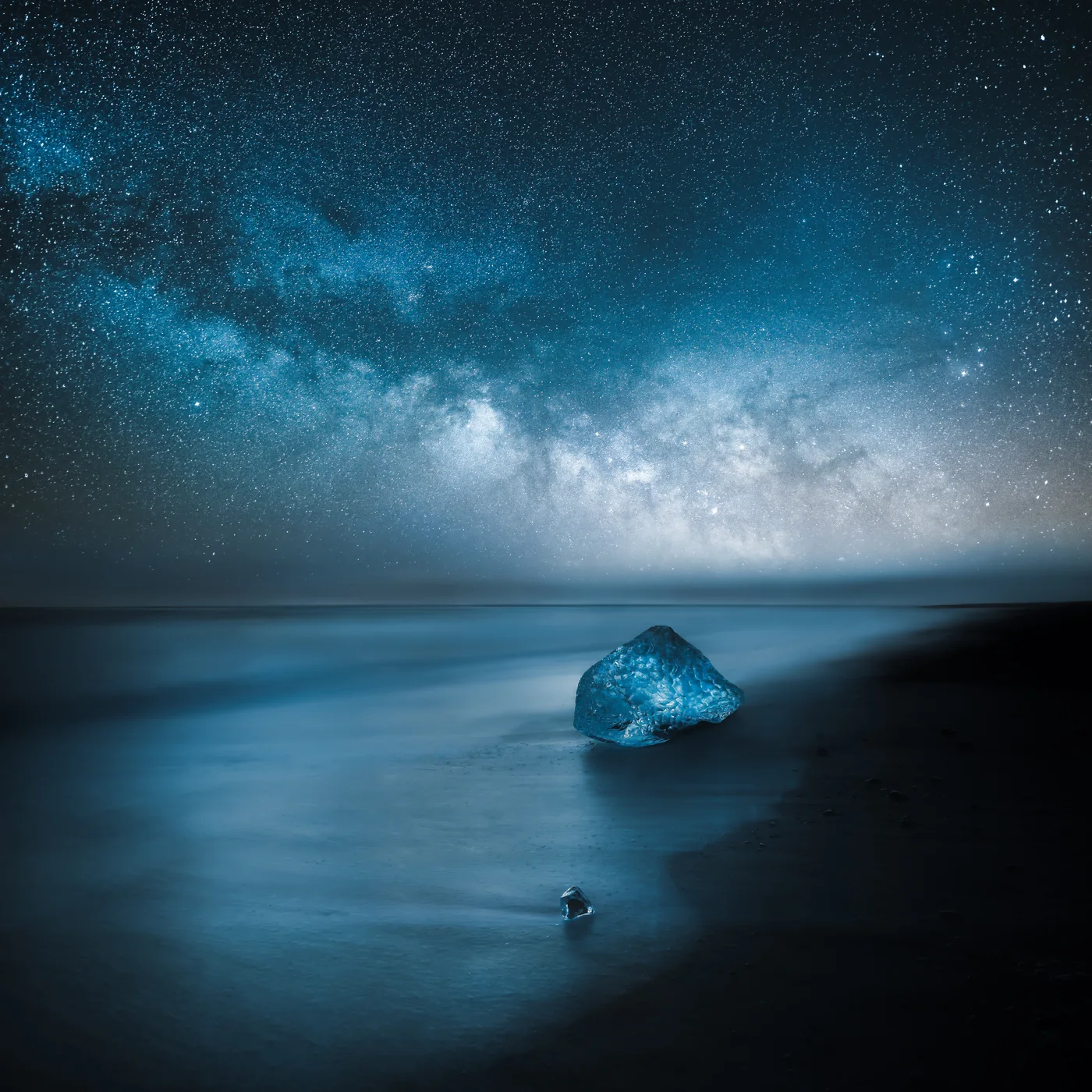 A lone figure and landscape transformed by light and weather at night.