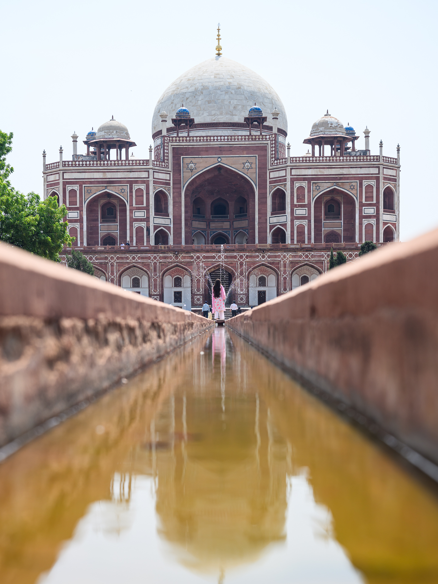 Humayun’s Tomb beyond a central water channel, with one visitor standing on the main axis.