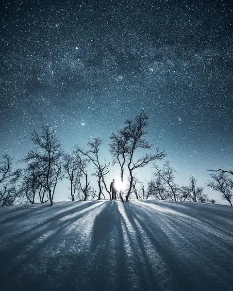 Solitary figure beneath a moonlit winter sky from the Alone gallery by Mikko Lagerstedt